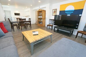 Ein modernes Wohnzimmer mit Couchtisch aus Holz, grauem Sofa und einem Fernsehschrank.