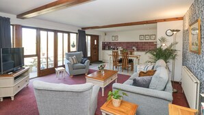 A living room with a television, sofas, a coffee table, and a dining area with chairs and a table. - Woodland View (Barnstaple)