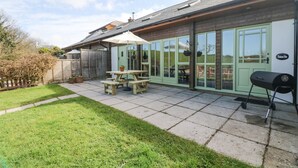 A patio with a picnic table, a grill, and a green door. - Woodland View (Barnstaple)