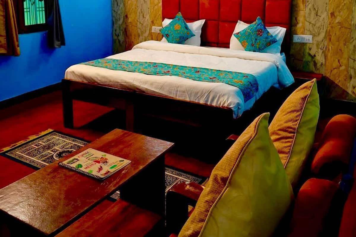 Een kamer met een bed, een slaapbank, een houten tafel en een kamerbreed tapijt.
