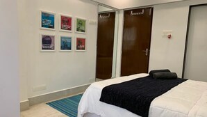 A bedroom with a bed, a blue mat, and six framed quotes on the wall.