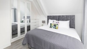 A modern bedroom with a large bed, a wardrobe, and a mirror.