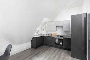 A modern kitchen with dark cabinetry, a countertop, and a built-in oven. - Skyvillion -vineyard Court Enfield 1bed Wbalcony (Enfield)
