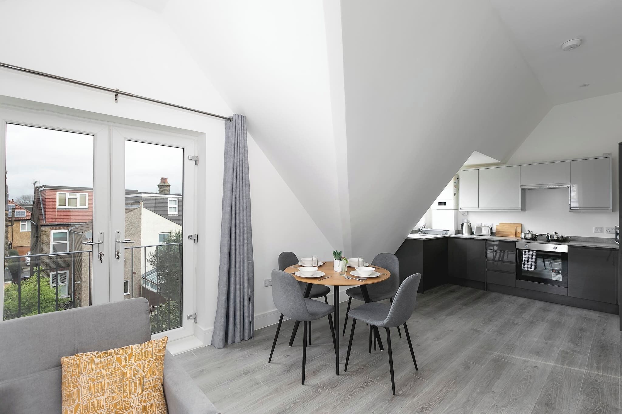 A modern apartment with a dining area, kitchen, and balcony.