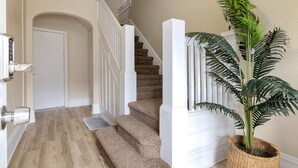 Un escalier avec des rampes blanches et des marches recouvertes de moquette, menant à une porte.