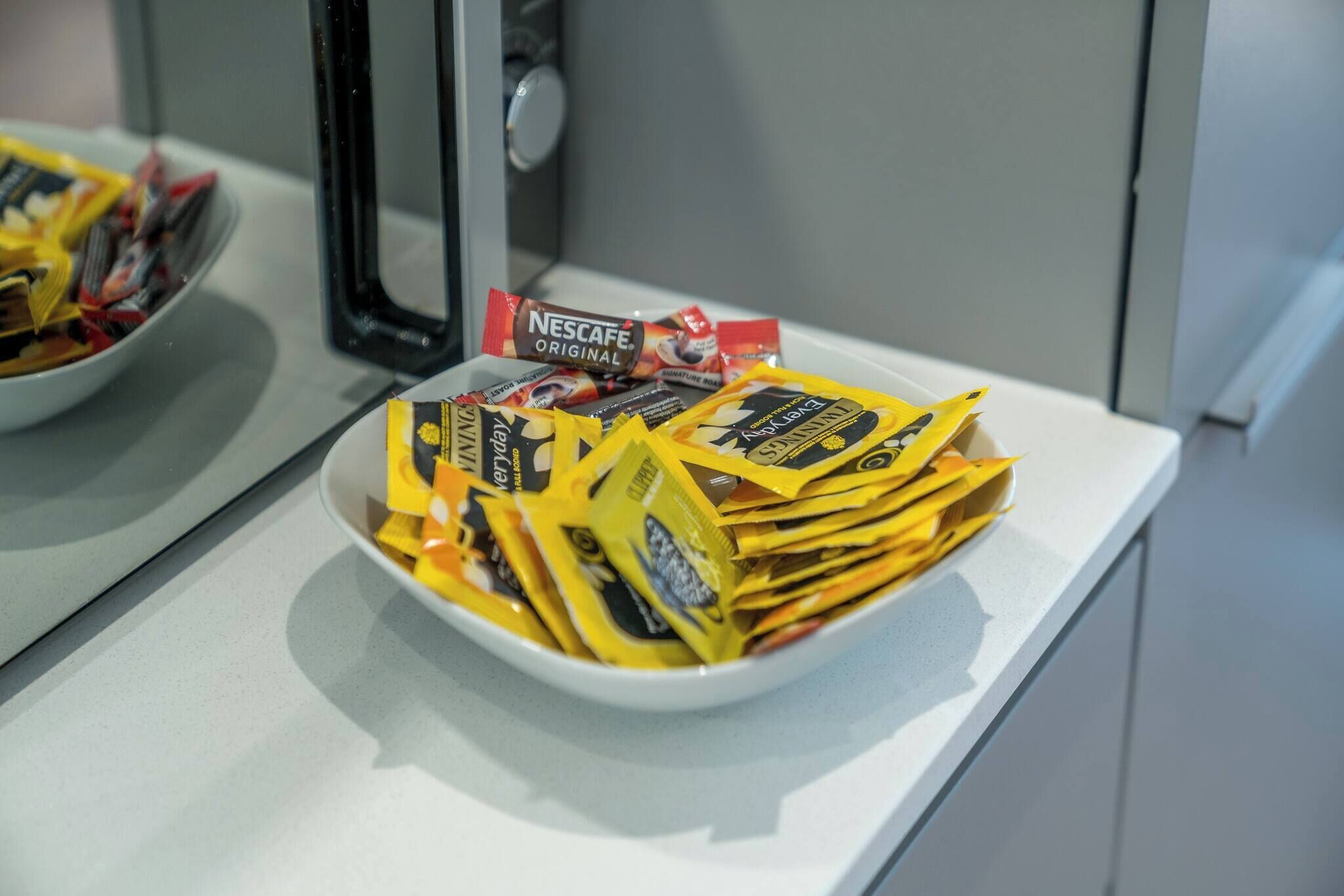 A bowl filled with yellow packets on a white countertop.