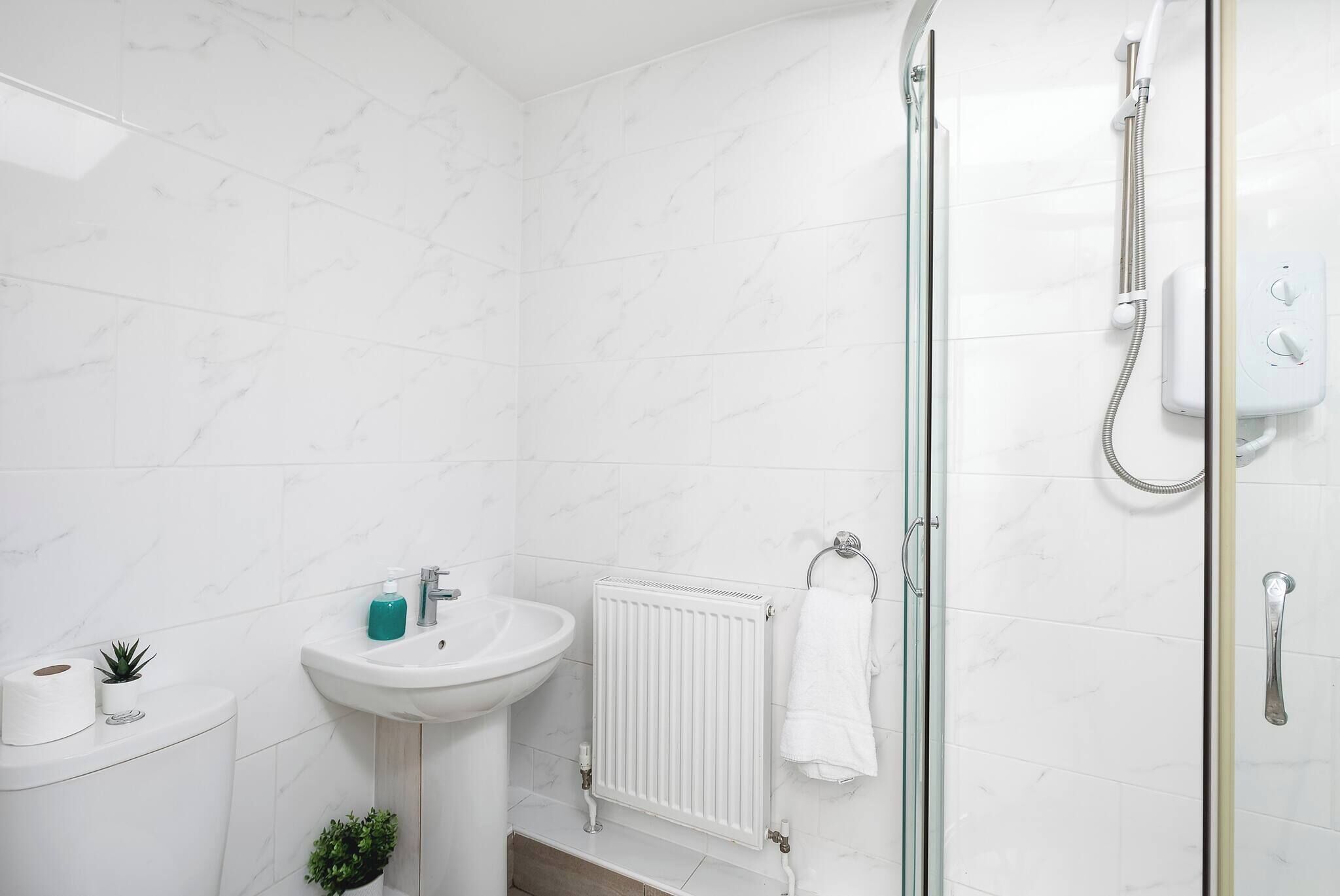 Un baño con lavamanos, inodoro y ducha blancos.