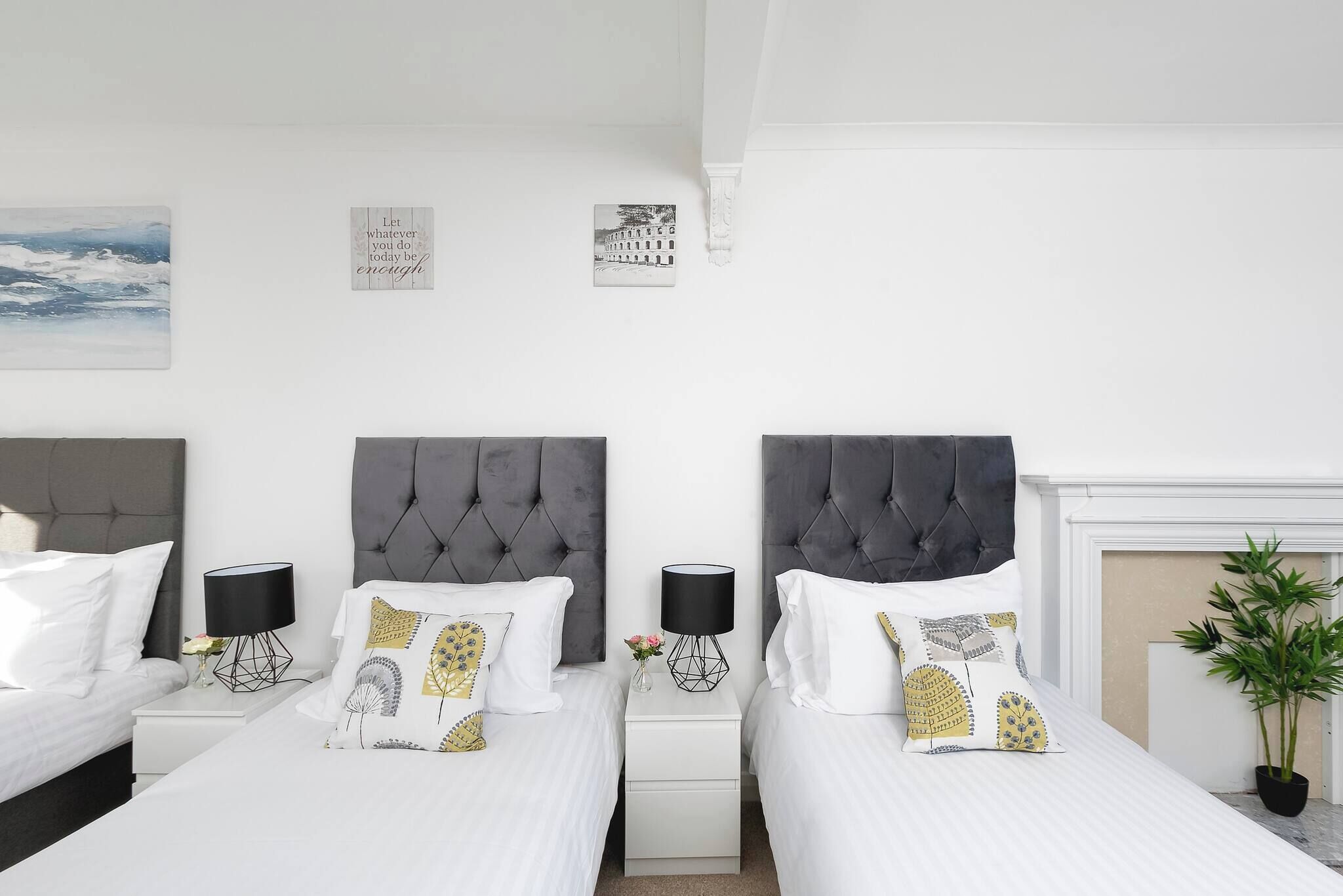 Hotellihuone, jossa on kaksi sänkyä, takka ja taideteoksia seinillä.