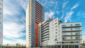 A modern high-rise building with multiple balconies and a flat roof.