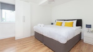 A bedroom with a bed, a wardrobe, a bedside table, and a window. - Skyvillion - Tower Point Enfield 1bed With Balcony (Enfield)