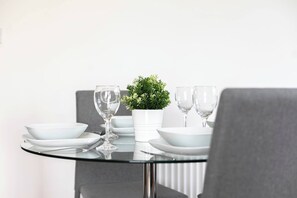 A dining table with white plates, glasses, and a potted plant. - Skyvillion - Huge 4bed Apartment Wbalcony - Parking (Enfield)