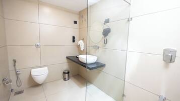 Een moderne badkamer met een douchecabine van glas, een wit toilet, een wastafel met een zwart aanrechtblad en een spiegel met een telefoon.