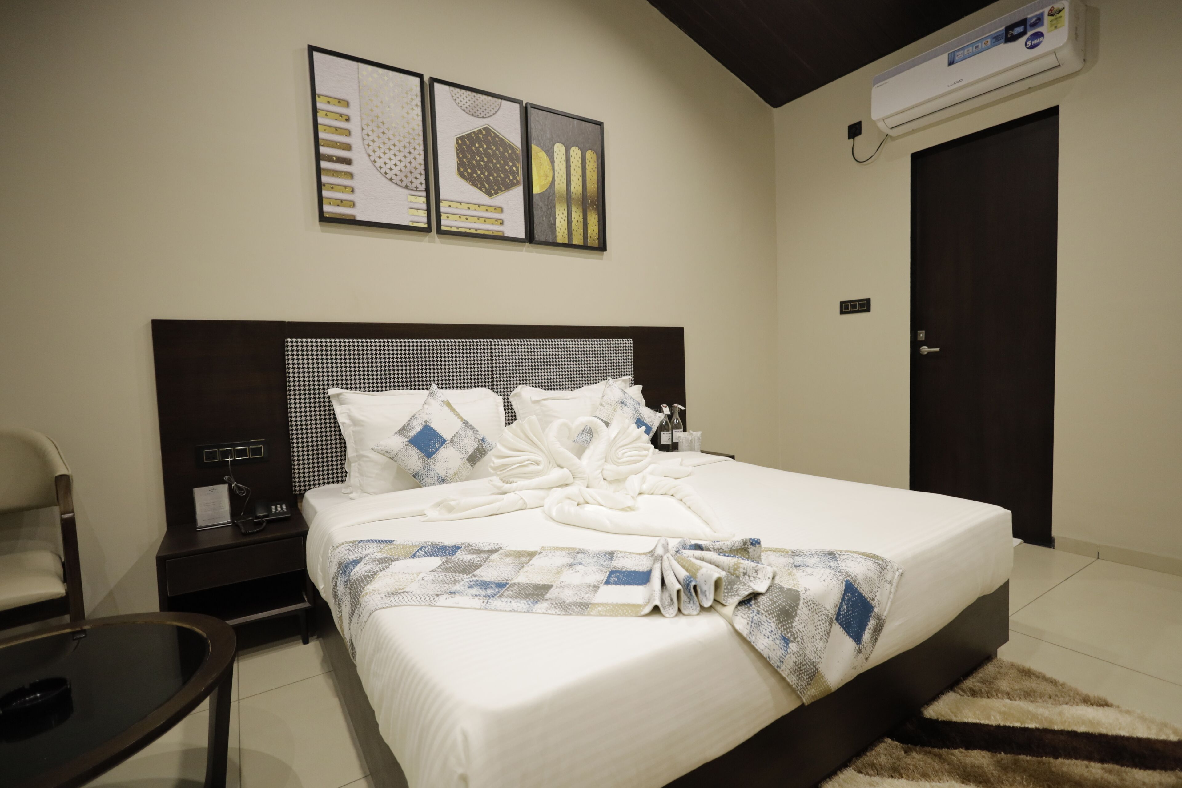 Una cama bien hecha con una colcha a cuadros, un cabecero con diseño geométrico y un aire acondicionado de pared.