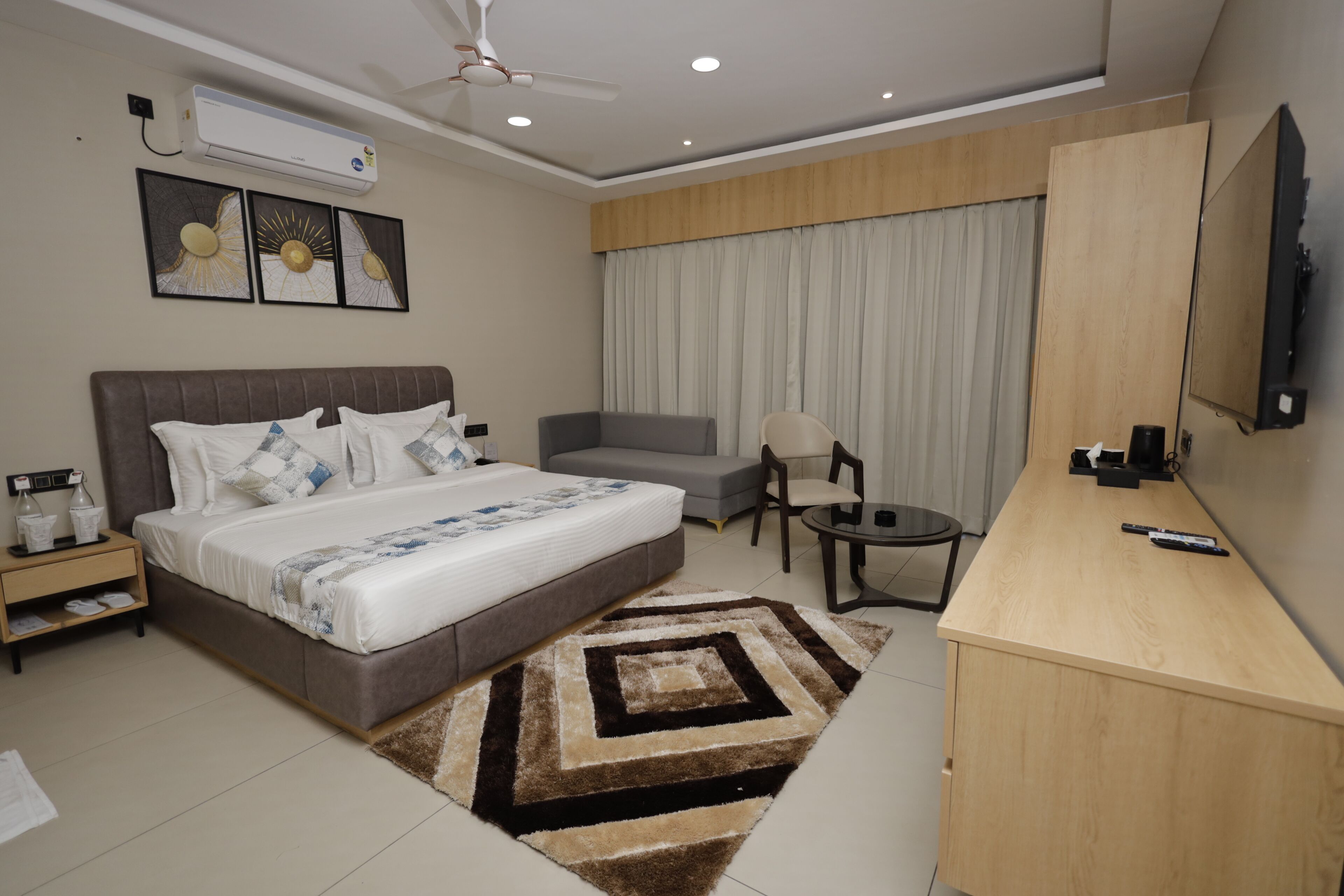 A modern hotel room with a large bed, a desk, a chair, and a TV.