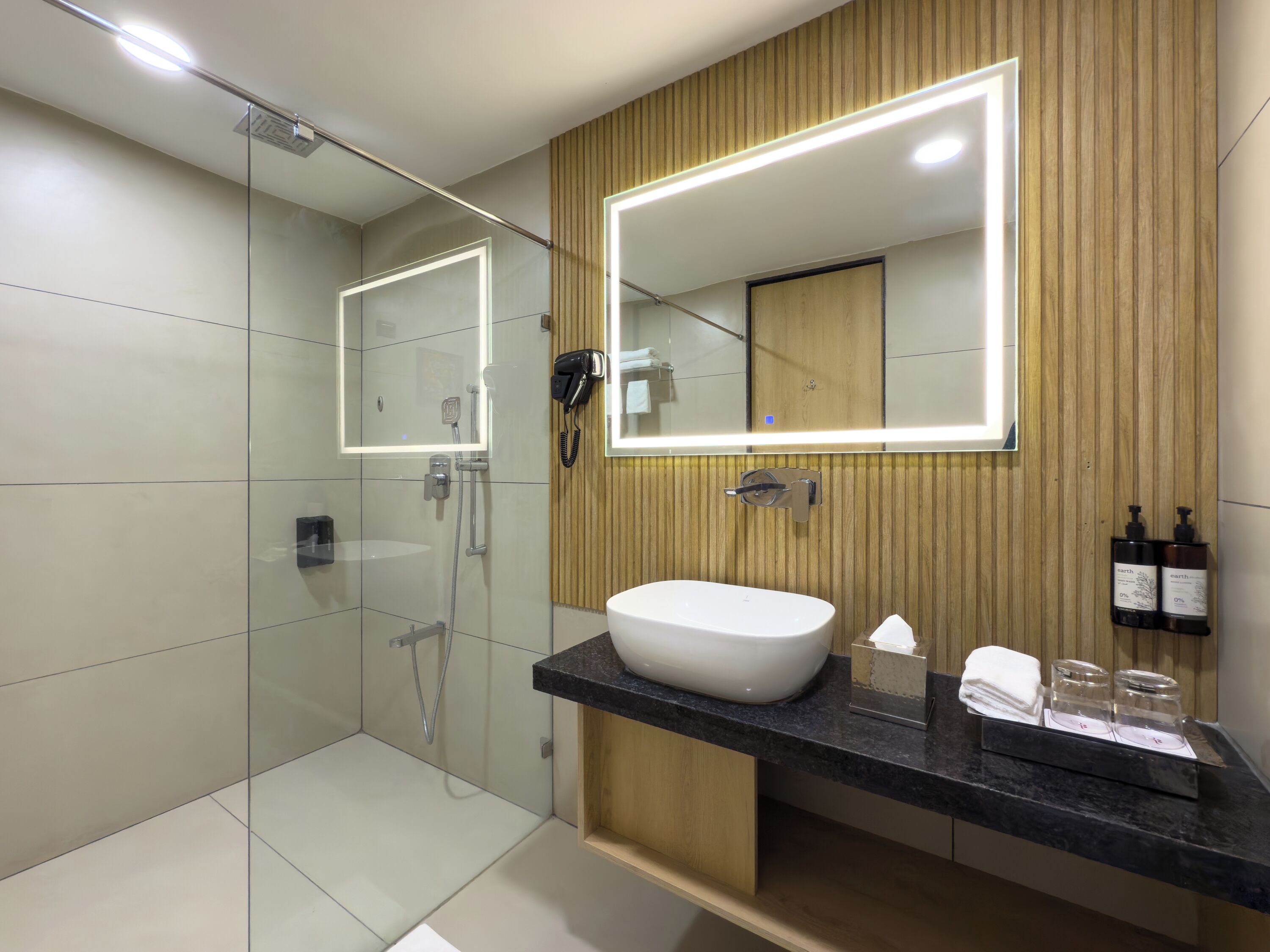 A modern bathroom with a glass-enclosed shower, a large mirror, a white sink, and wooden paneling.