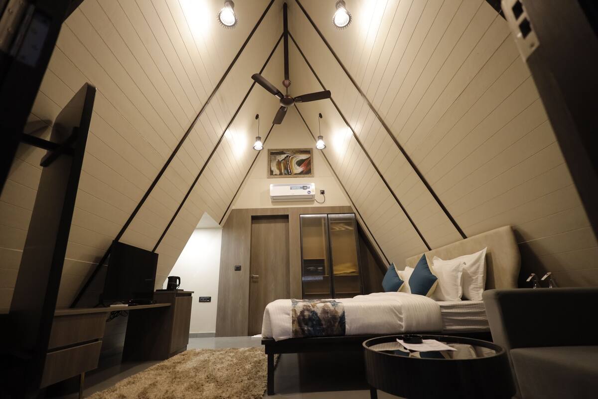 A cozy, triangular room with a bed, a desk, and a ceiling fan.