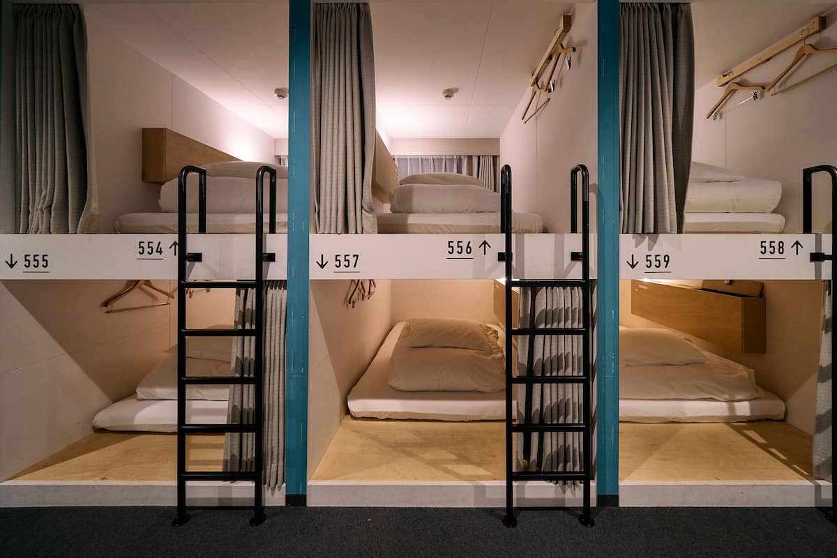 A row of bunk beds with numbers indicating room assignments, a wooden ladder, and a wall-mounted hanger.