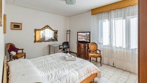 A hotel room with a bed, a television, a desk, and a chair.