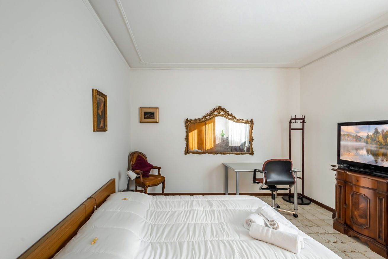 Habitació d'hotel amb llit, escriptori, cadira, televisió i mirall.
