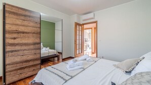 Un dormitorio con una cama, un armario de madera, una pared verde y una puerta que da al baño.