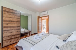 A bedroom with a bed, a wooden wardrobe, a green wall, and a door leading to a bathroom. - GuestHost - Modern and spacious apartment is located in a prestigious area of the city near the Polytechnic, situated less than 2 km away, and well connected to the historic center thanks to public transport that allows you to reach all points of interes (Torino)