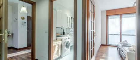 A modern apartment with a laundry area, a kitchenette, and a bedroom with a view.
