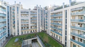 Un edificio residencial de varios pisos con balcones, un patio central y un techo plano.