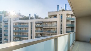 Un edificio residencial de varios pisos con balcones, piso de baldosas y cielo despejado.