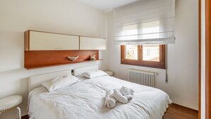 Une chambre à coucher avec un lit, une table de chevet et une fenêtre avec des stores.