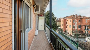 Un balcon donnant sur les immeubles voisins, une porte et un appareil de climatisation.