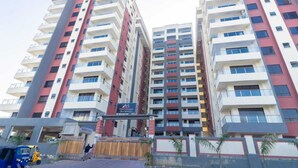 Un edificio residencial de varios pisos con balcones, una entrada protegida por una reja y un letrero que indica un hotel.