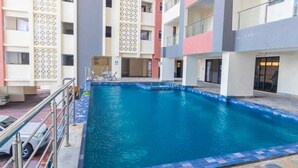 Una piscina con borde de azulejos, rodeada de edificios con múltiples pisos y balcones.