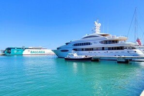 Um iate grande atracado em um porto, com um barco menor por perto.