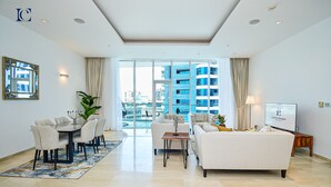 A modern living room with a dining area, large windows, and a view of high-rise buildings. - Premium 3BR Partial Sea View OCEANA (Dubai)
