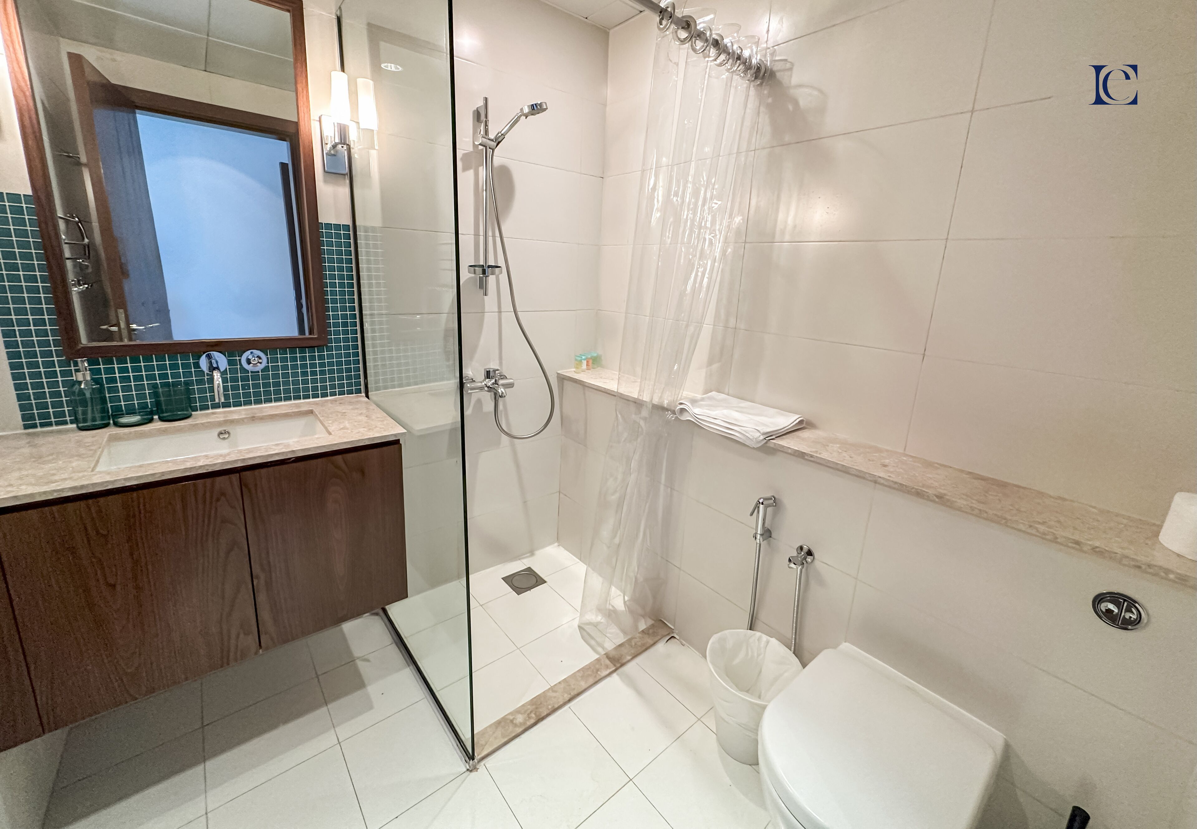 A modern bathroom with a glass-enclosed shower, a white toilet, and a vanity with a mirror.