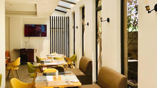 A modern dining area with a long table, yellow chairs, and a brown sofa. - Cot Hotel (Addis Ababa)