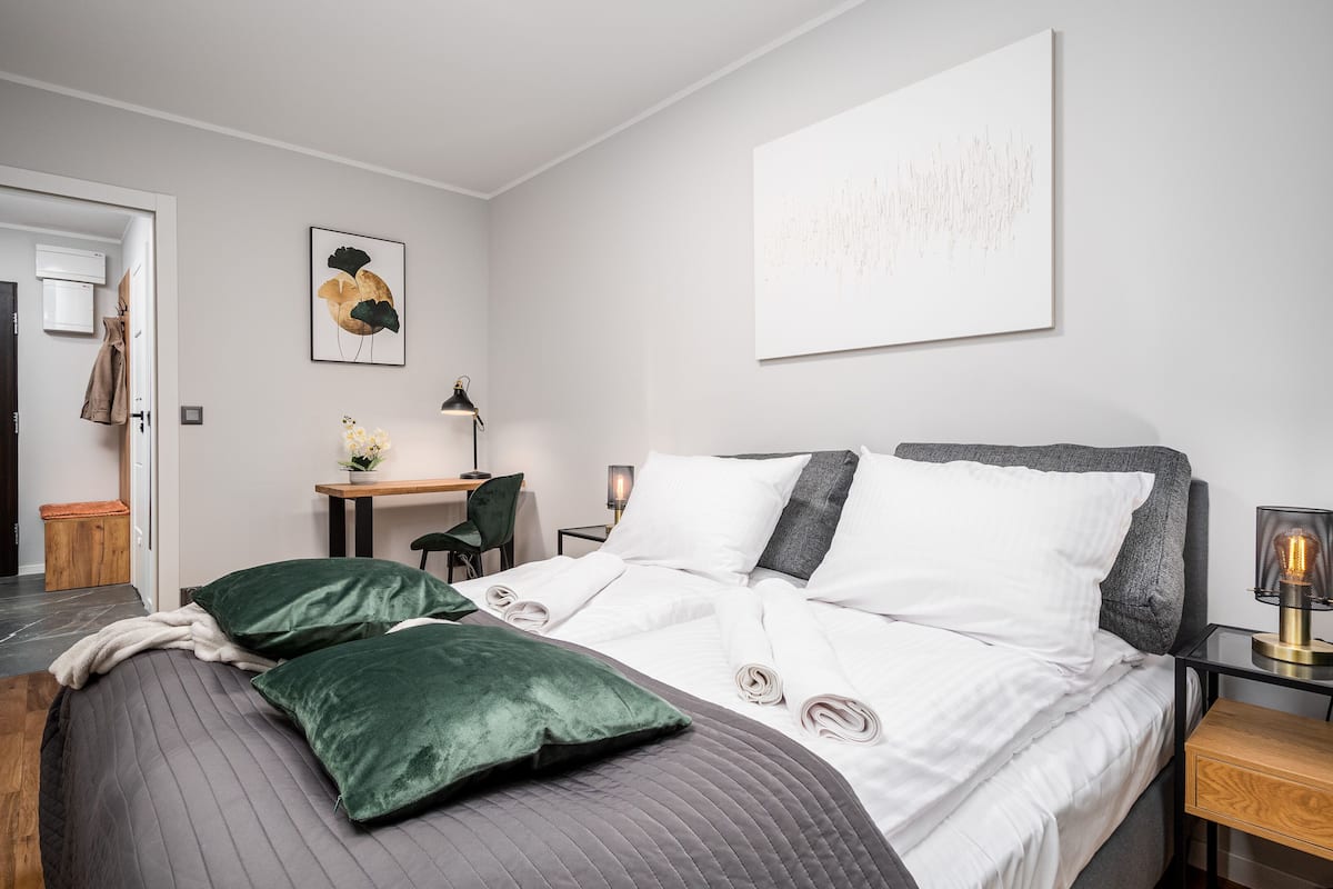 A modern hotel room with a bed, a desk, a chair, and a small table.