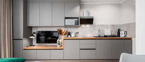 Una cocina moderna con armarios grises, un televisor de pantalla plana, un microondas y una cafetera.