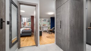 Ein modernes Schlafzimmer mit Bett, Nachttisch und Blick auf die Stadt durch große Fenster.