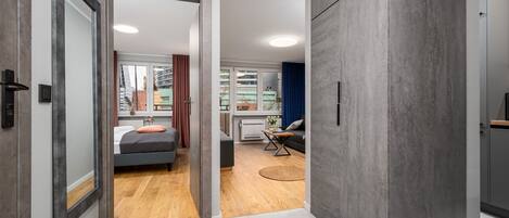 Un dormitorio moderno con cama, mesita de noche y vistas a la ciudad a través de amplias ventanas.