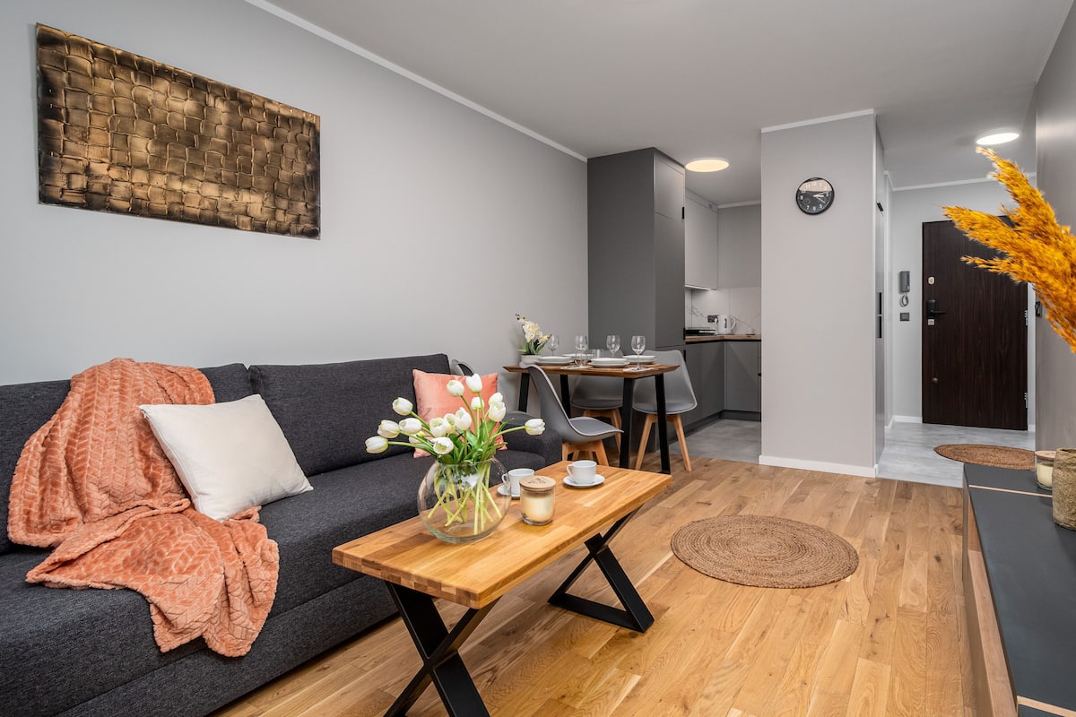 A modern living room with a sofa, coffee table, and a dining area.