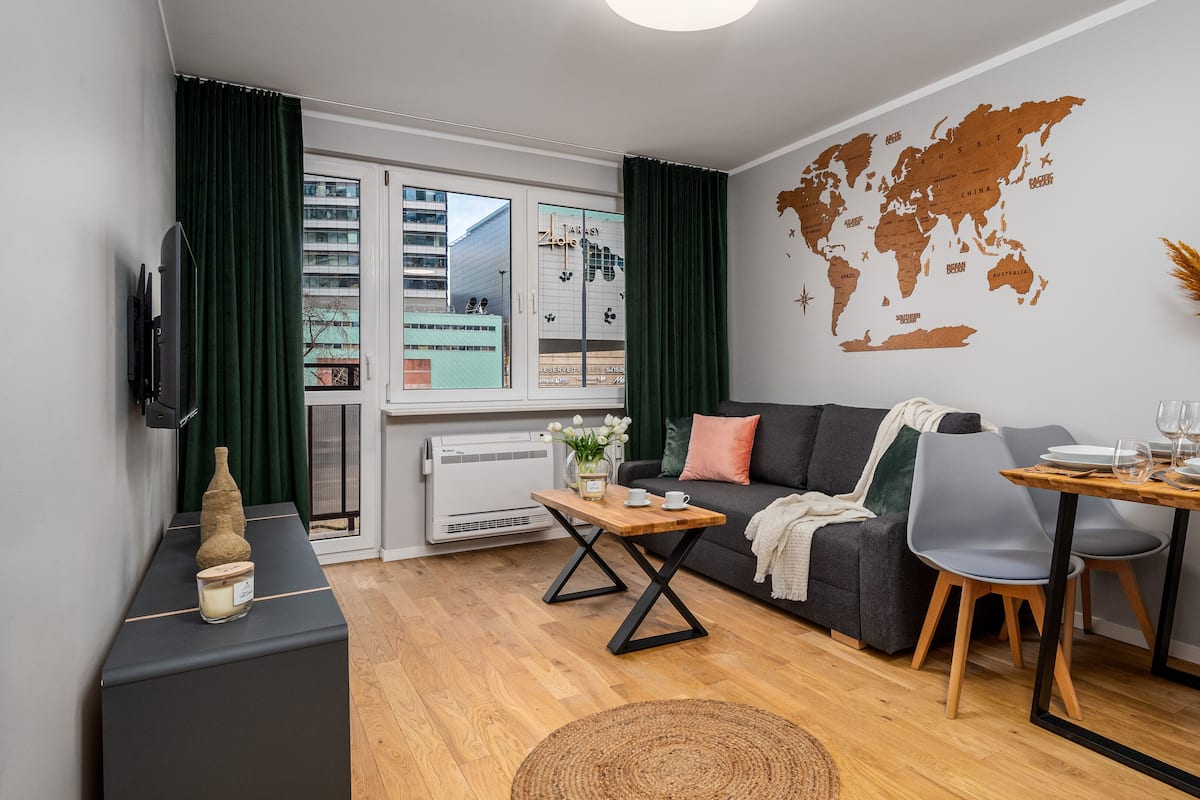 A modern living room with a sofa, dining table, and a world map on the wall.