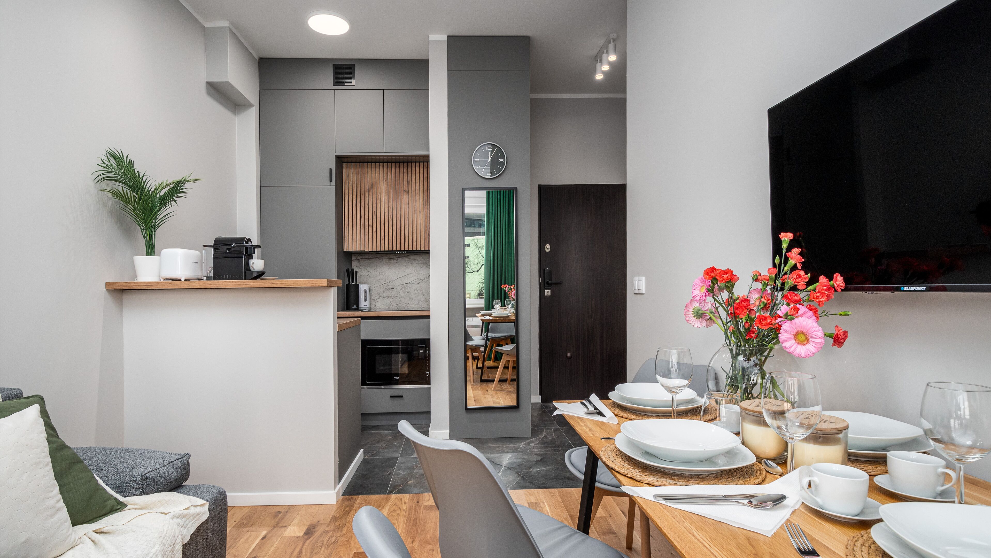 A modern kitchen with a built-in microwave, a coffee machine, and a dining area with a table set for two.