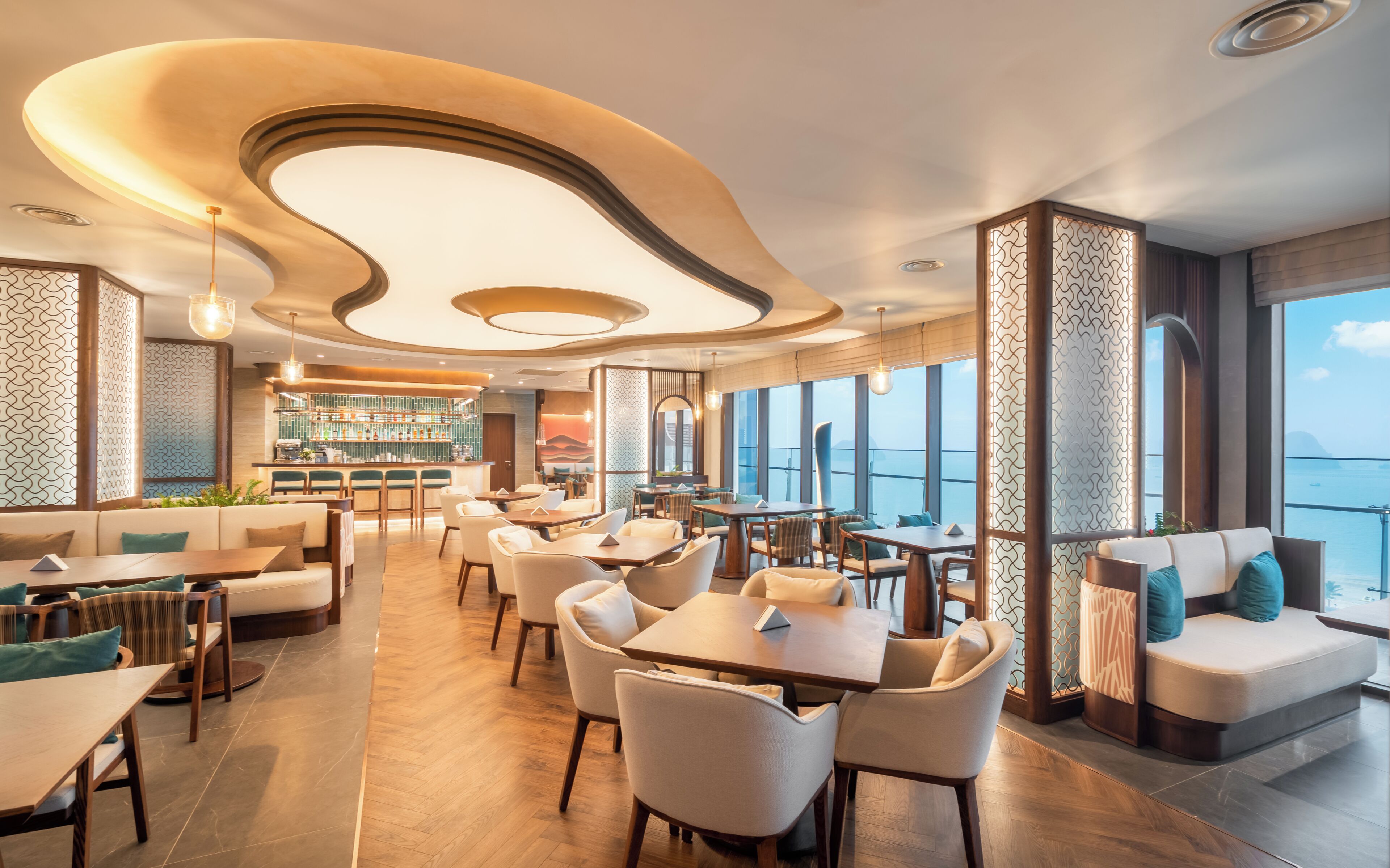 A modern restaurant with a bar area, seating arrangements, and large windows offering a view.