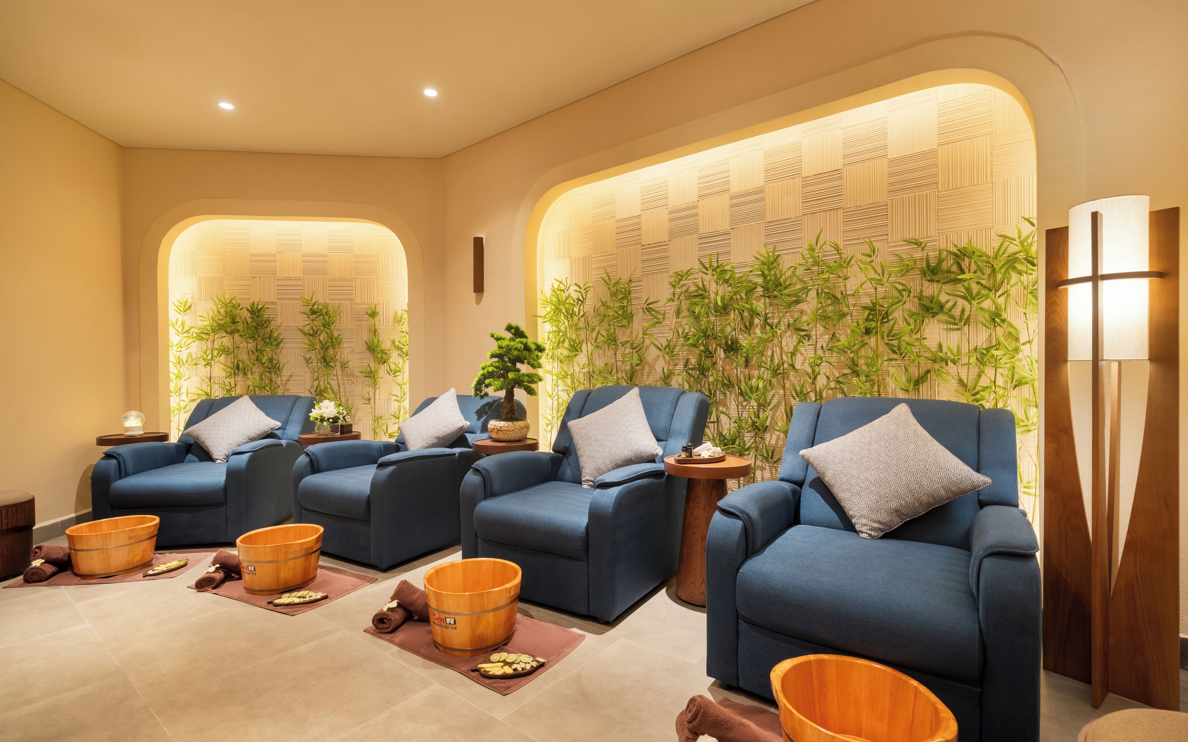 A spa area with four blue chairs, wooden buckets, and a bamboo wall.