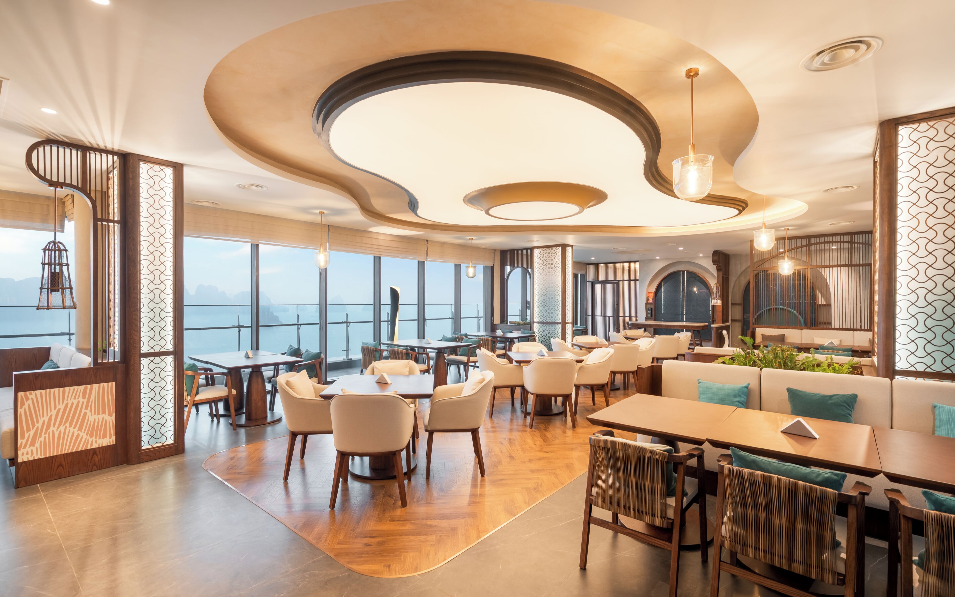 A modern hotel interior with a panoramic sea view, wooden flooring, and contemporary furniture.