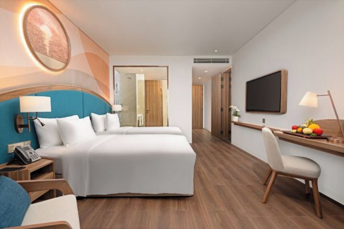 Una habitación de hotel con cama, mesita de noche, lámpara y escritorio con silla.