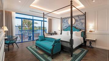 A four-poster bed with a view of palm trees, a teal sofa, and a patterned rug.