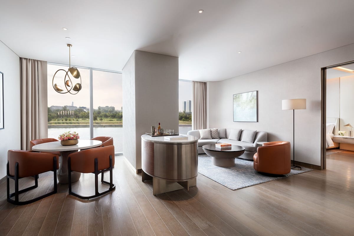 A modern living room with a round dining table, orange chairs, a sofa, and a coffee table.