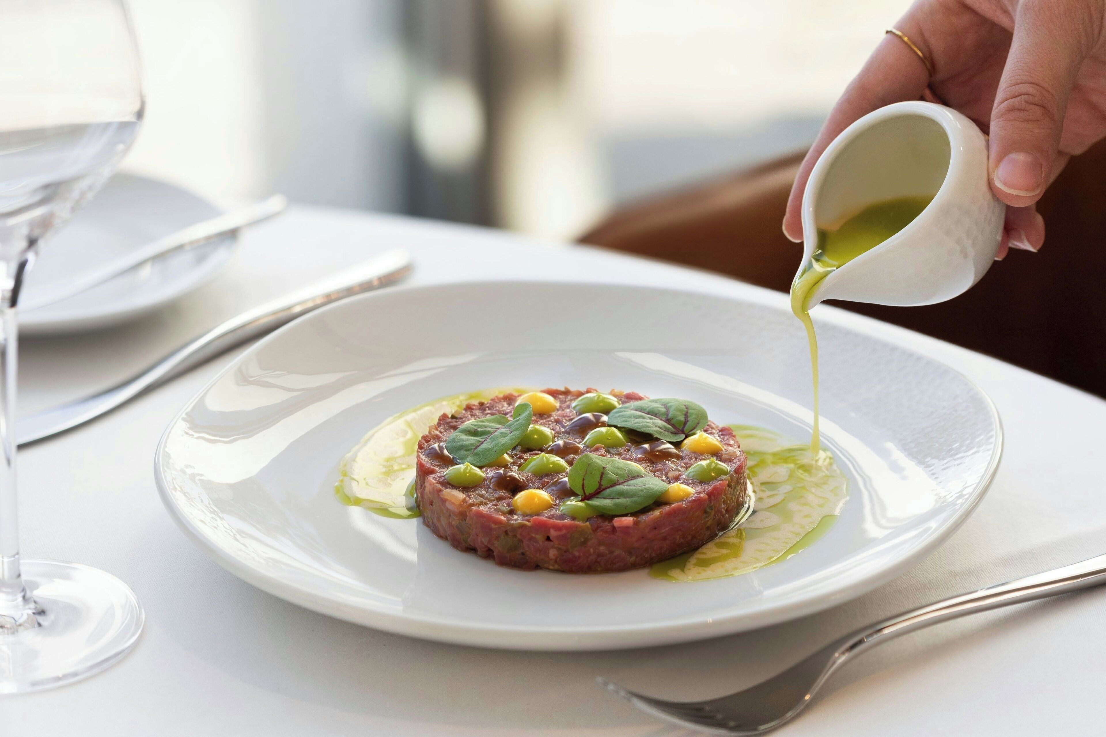 Un piatto di tartare di manzo con salsa che viene versata sopra.